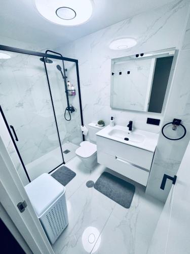 a white bathroom with a shower and a sink at EliMar-Torrevieja Beach in Torrevieja