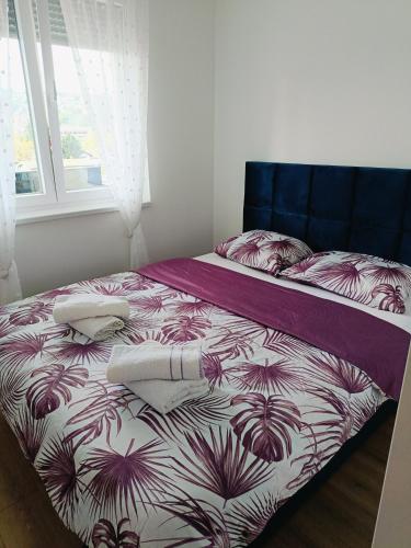 a bedroom with a bed with a purple and white comforter at Fort view in Doboj