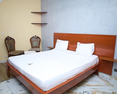 - un lit dans une chambre avec 2 chaises dans l'établissement Résidence HQ, à Brazzaville