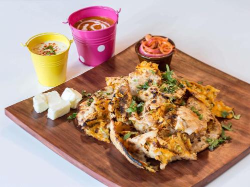 Ein hölzernes Schneidebrett mit einer Pizza und einigen Getränken in der Unterkunft ibis Jaipur City Centre - An Accor Brand in Jaipur