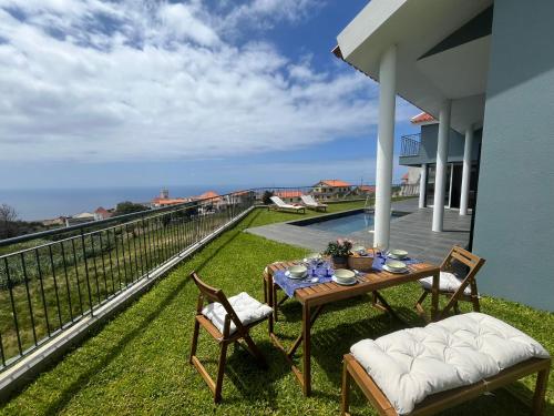 a table and chairs on the balcony of a house at Sunset Cottage - Special Places in Ponta do Pargo