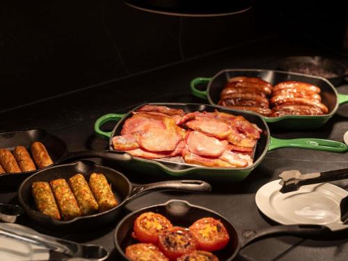 Una mesa cubierta con bandejas de comida y pasteles. en Mercure Manchester Norton Grange Hotel & Spa, en Rochdale