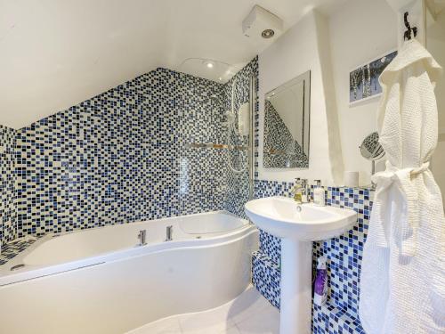 a bathroom with a white tub and a sink and a bath tubermott at 1 Bed in Evesham 55177 in Bretforton