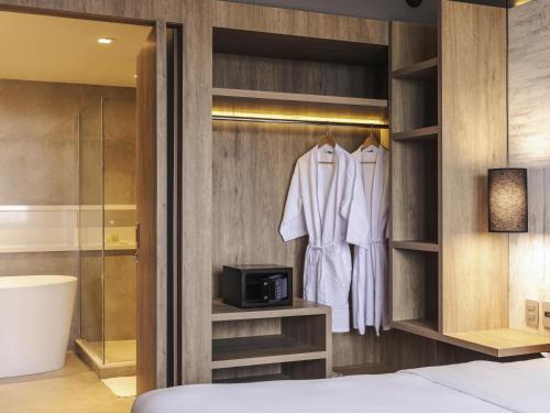 a bedroom with a closet with white clothes and a television at Novotel Porto Alegre Airport in Porto Alegre
