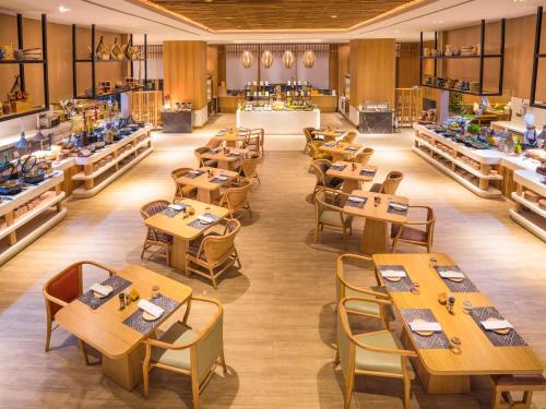 a restaurant with wooden tables and chairs in a room at Novotel Hyderabad Airport in Hyderabad