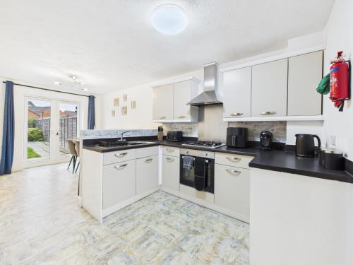 a kitchen with white cabinets and black counter tops at Spacious 5 Bed Contractor Hub 3 Baths Corby in Corby