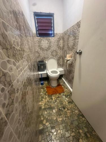a small bathroom with a toilet and a window at Tiares Homestay in Suva