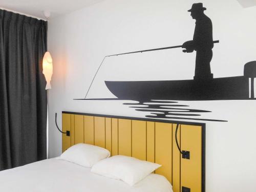 a bedroom with a bed and a man on a boat at ibis Styles Macon Centre in Mâcon