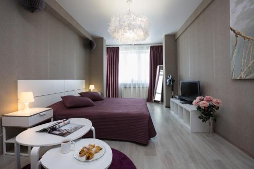 エカテリンブルクにあるEtazhiDaily at Kosmonavtovのベッドとテーブルが備わるホテルルームです。