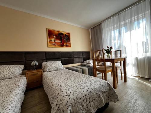 une chambre avec deux lits, une table et une chaise dans l'établissement Willa Wiosenna, à Kołobrzeg
