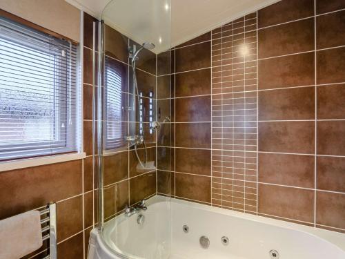 a bathroom with a tub and tiled walls at 3 Bed in Windermere 90476 in Troutbeck