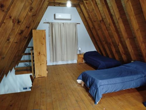 a attic room with two beds and a staircase at La Cabaña de Lali in Monte Hermoso