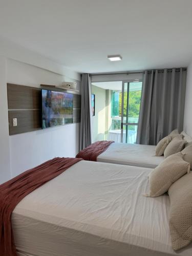 two beds in a hotel room with a window at Flat a Beira Mar em Carapibus PB in Conde