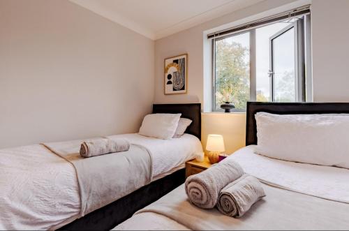 two beds in a room with a window at Contractor-Friendly, Private Gated Parking, Fast WiFi, Sofa Bed & Netflix, 5-Min Walk to City Centre, 15-Min Walk to Train Station, Ideal for Relocators & Families in Coventry