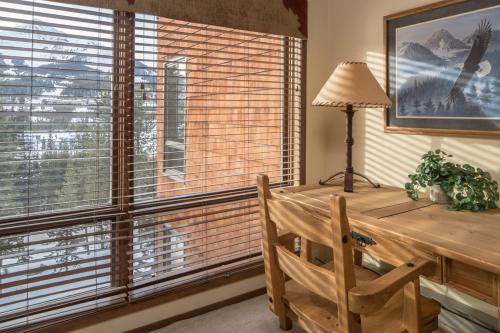 a wooden desk with a lamp and a chair next to a window at Skycrest 1714 in Big Sky