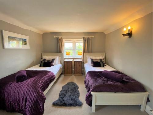 two beds in a room with purple comforters at 4 Bed in Ningwood IC048 in Newbridge