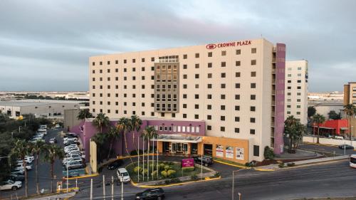 a large white building in a city with a parking lot at Crowne Plaza Monterrey Aeropuerto by IHG in Monterrey