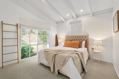 a white bedroom with a large bed and a window at Backbeach House 1km to Beach in Blairgowrie