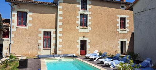 a building with a swimming pool with chairs and a building at Le havre de faye in Savigny-sous-Faye