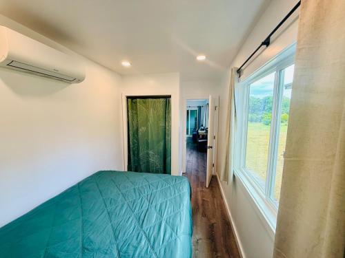a bedroom with a bed and a large window at Hibiscus Hale - Perfect for 2! in Waialua