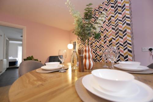a dining room table with white plates and wine glasses at Stylish central location 3 bedroom house in Ely