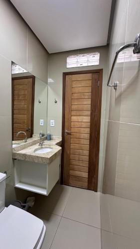 a bathroom with a sink and a toilet and a mirror at Casa Gold Condominio Estancia Jussara in Barreirinhas