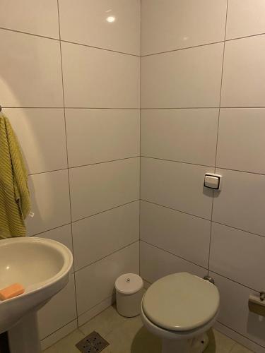 a white bathroom with a toilet and a sink at Pousada Zona 7 in Maringá