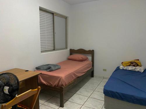 a bedroom with two beds and a desk and a window at Pousada Zona 7 in Maringá