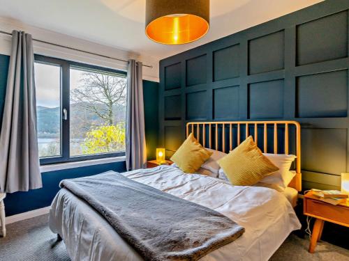a bedroom with a large bed with a blue wall at 3 Bed in Pitlochry CA207 in Struan