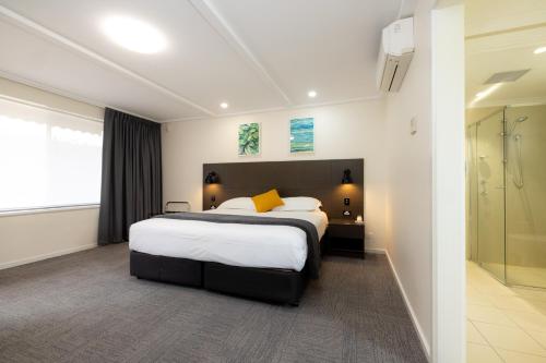 a hotel room with a large bed and a shower at Mick O'Sheas in Hackham
