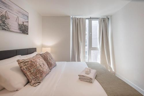 a bedroom with a white bed with a window at Cozy Corner - Modern 1BR in MTL in Montréal
