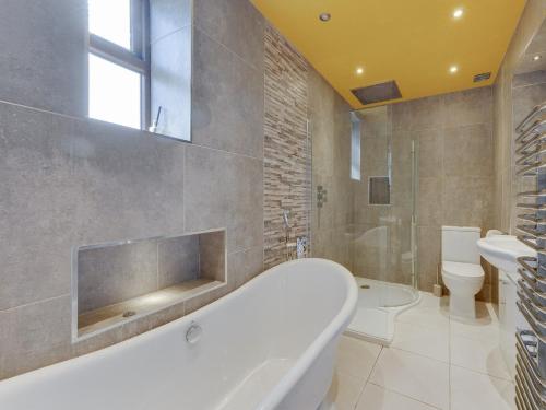 a bathroom with a tub and a toilet and a sink at 5 Bed in Haworth 88390 in Oxenhope