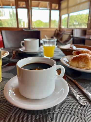 eine Tasse Kaffee auf einem Tisch mit einem Teller in der Unterkunft Land Park - Hostería y Cabañas in Junín de los Andes