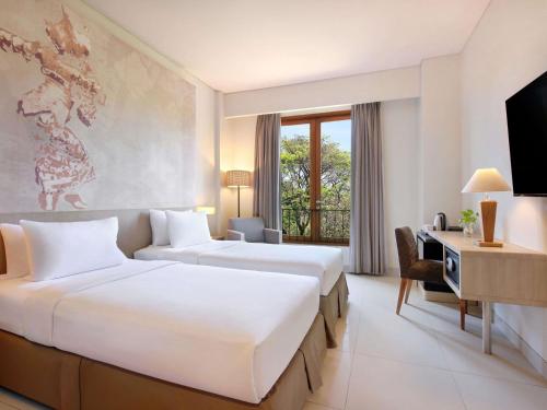 a hotel room with two beds and a desk at Mercure Bali Nusa Dua in Nusa Dua