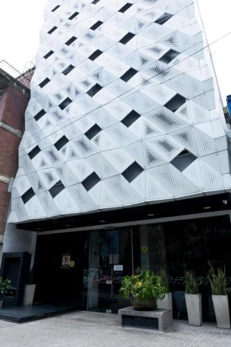 a building with a geometric facade with potted plants in front of it at ExpoStay Hotel Corferias Embajada Americana in Bogotá