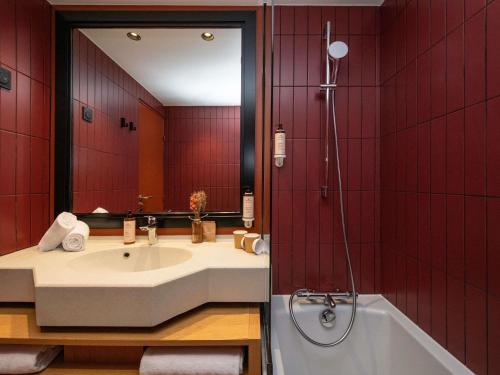 a bathroom with a tub and a sink and a mirror at Mercure Toulouse Aéroport Golf de Seilh in Seilh