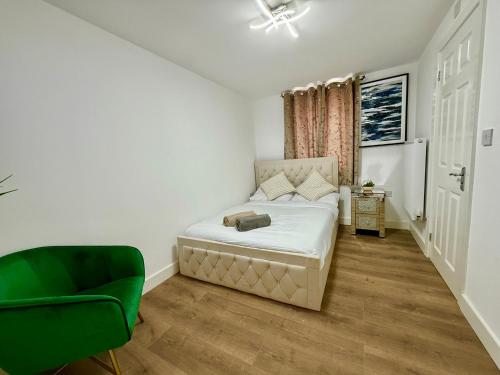 a small bedroom with a bed and a green chair at DSK Residencia in Maidstone