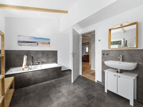 a bathroom with a sink and a tub and a mirror at Wilma - direkt an der Ostsee in Zierow