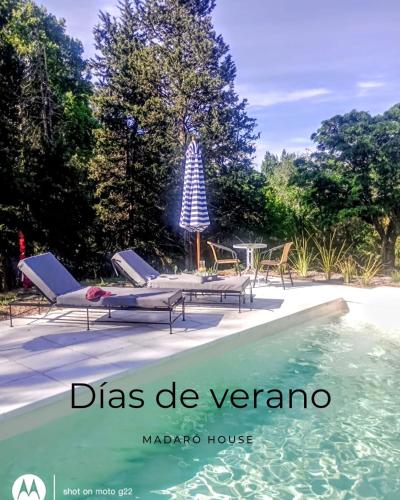 una piscina con sillas, una mesa y una sombrilla en Madaro House, en San Antonio de Arredondo