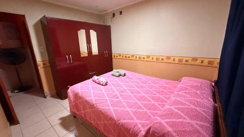 a bedroom with a pink bed with a stuffed animal on it at Hospedaje Maité in Santa María