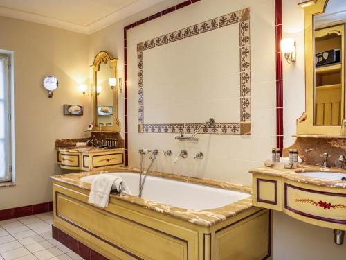 a bathroom with a tub and a sink at Hotel de la Cité Carcassonne - MGallery Collection in Carcassonne