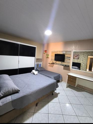 a bedroom with two beds and a flat screen tv at Espaço Foz com piscina e garagem gratuita in Foz do Iguaçu