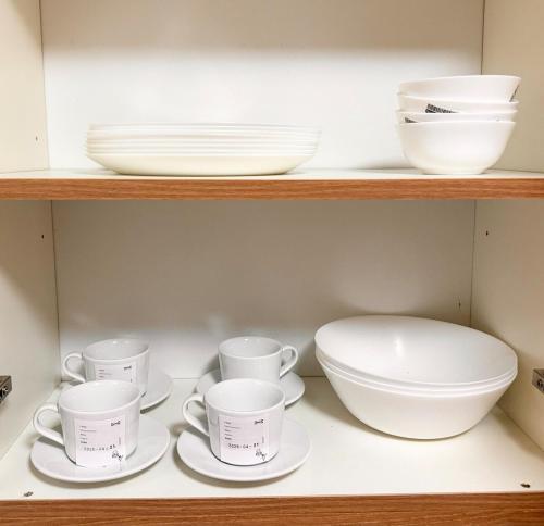 a shelf with cups and plates and bowls on it at Staycacia Haven 2BR Condo Maple Acacia Taguig in Manila