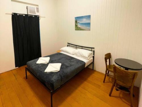 a bedroom with a bed and a table and a table and chairs at The Grand Hotel Cairns in Cairns