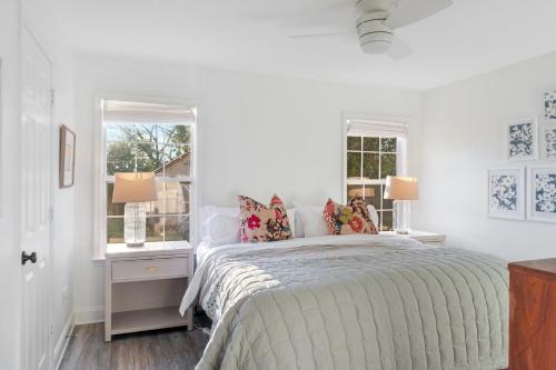 a white bedroom with a bed and two windows at The Clover Cottage in Normaltown in Athens