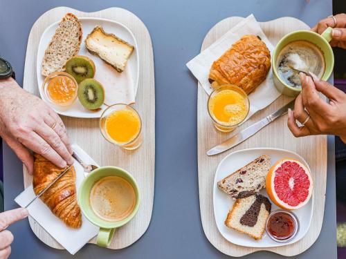 una mesa con dos platos de comida y bebida para el desayuno en ibis Styles Annecy Centre Gare, en Annecy