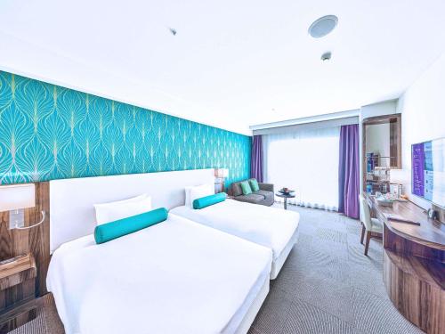 a hotel room with two beds and a desk at Mercure Okinawa Naha in Naha
