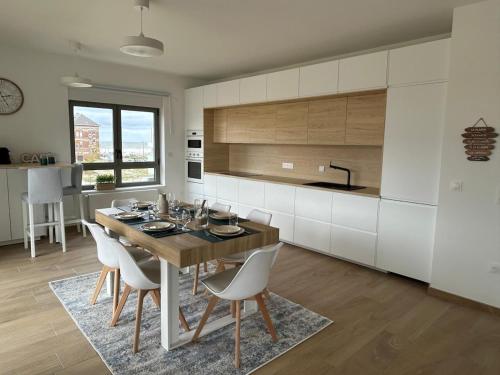 eine Küche mit einem Holztisch und weißen Schränken in der Unterkunft Les Terrasses du Phare, vue mer, 100m plage, pkg, terrasses, accès PMR in Berck-sur-Mer