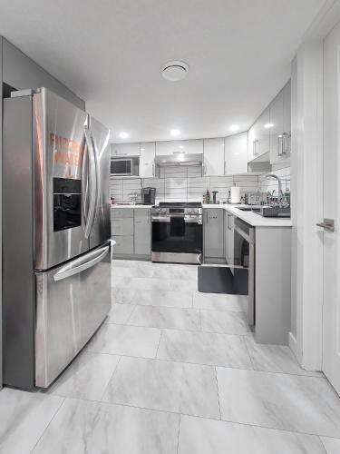 a large kitchen with stainless steel appliances and white cabinets at Superior and Spacious 2-bedroom basement private suite in Edmonton