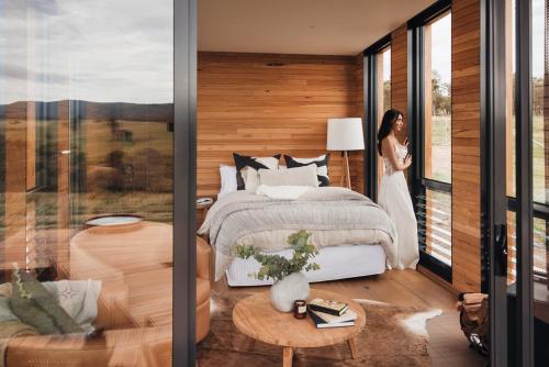 a woman standing in a bedroom with a bed at Gabarraa Luxury Escape in Tenterfield